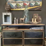 Stoer dressoir van teakhout met vier stoere zwart stalen lades. Tussen het blad en de lades zit een speelse tussenruimte.