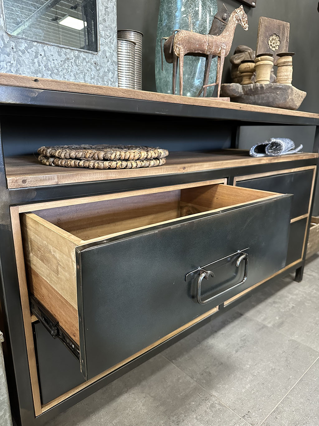 Stoer dressoir van teakhout met vier stoere zwart stalen lades. Tussen het blad en de lades zit een speelse tussenruimte.