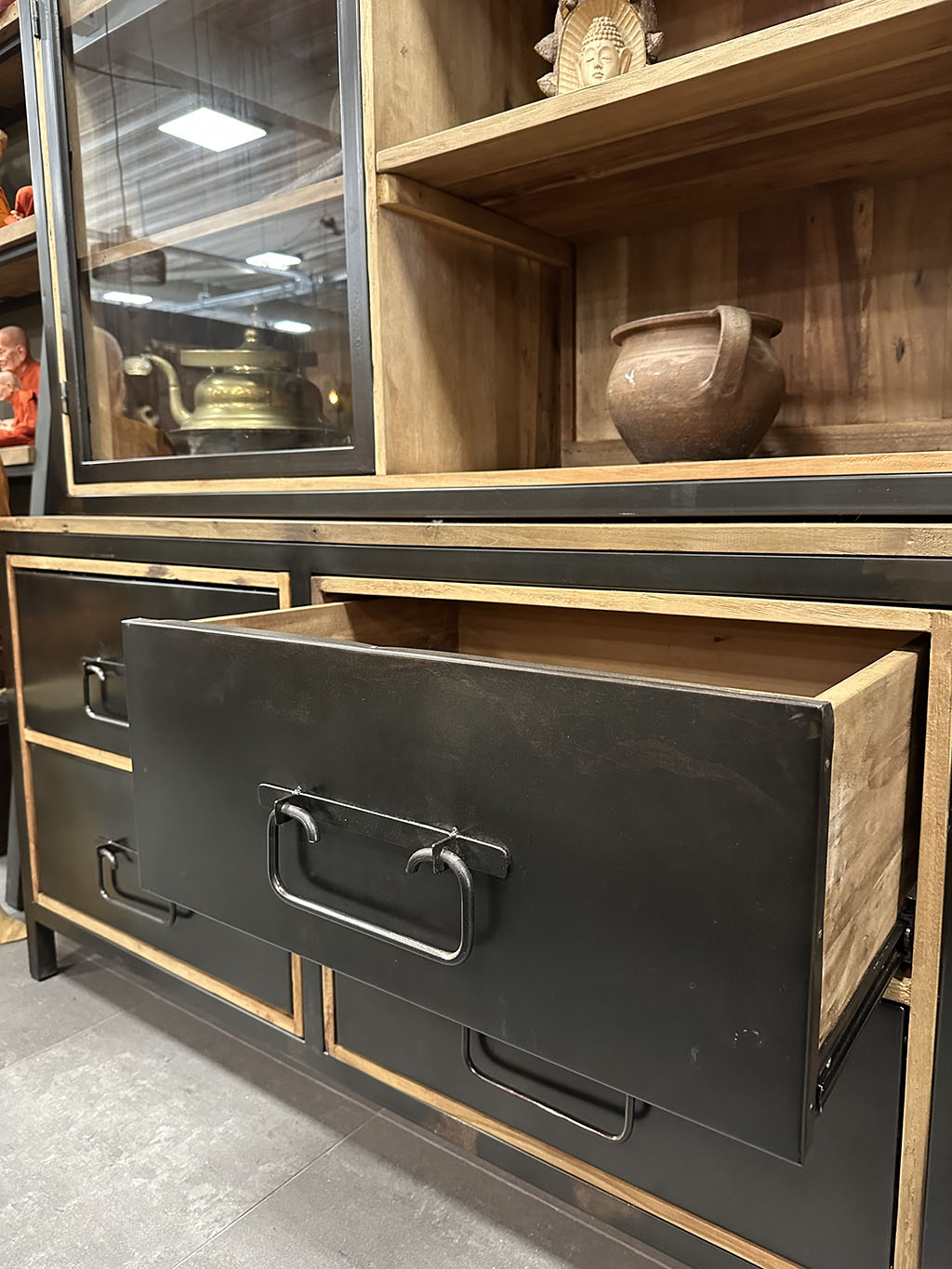 Stoer dressoir van teakhout met vier stoere zwart stalen lades. Tussen het blad en de lades zit een speelse tussenruimte.