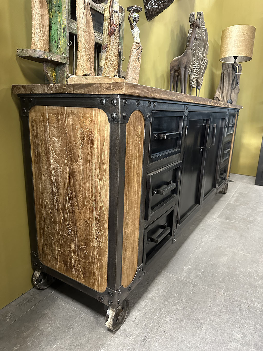 Dressoir Yordi is een stoere kast gemaakt van staal en geleefd hout. De kast bestaat uit zes lades met in het midden opbergruimte achter twee deurtjes.