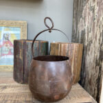 Stoer rond blik met handvat, roestig getinte hang pot van staal, perfect voor groene hangplanten.