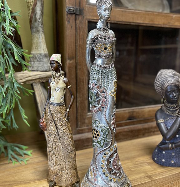 Slank decoratief vrouwenbeeld met verfijnde patronen en wereldse uitstraling op een houten dressoir.