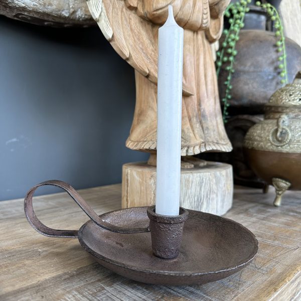 Gietijzeren kandelaar met oor en roestbruine afwerking op een houten dressoir.