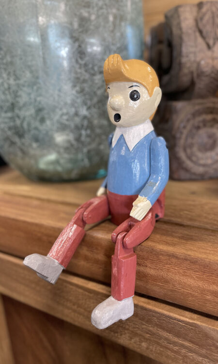 Houten bungelpop van Kuifje met beweegbare benen zittend op een houten kast als decoratie