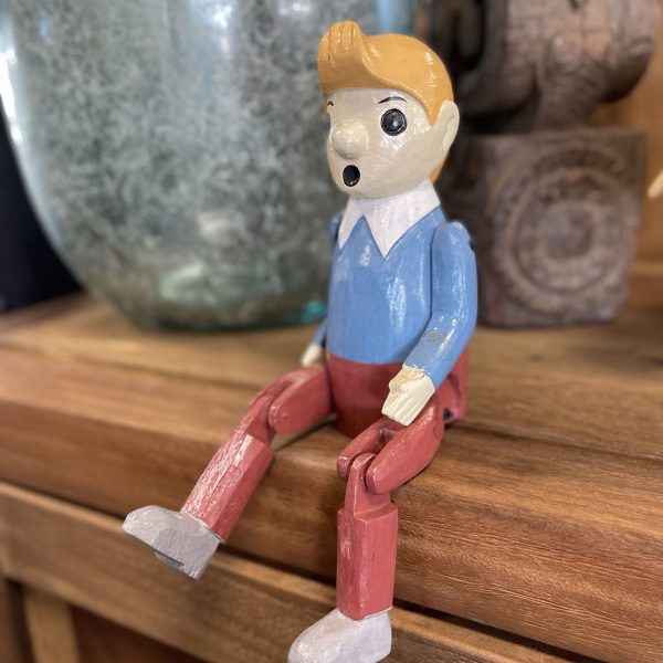 Houten bungelpop van Kuifje met beweegbare benen zittend op een houten kast als decoratie